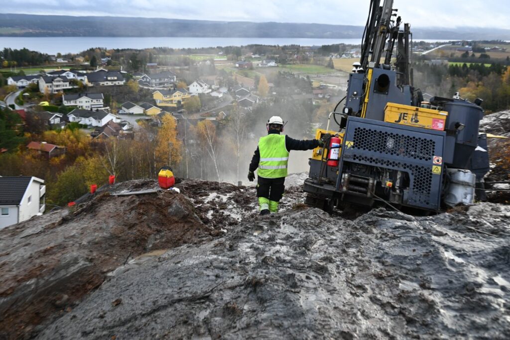 Mann på anleggsplass med digital sprengningsdokumentasjon som bidrar til tryggere sprengning.