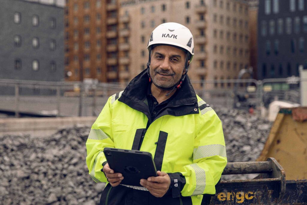 Arbeider på byggeplass bruker nettbrett for HMS- og KS-styring.